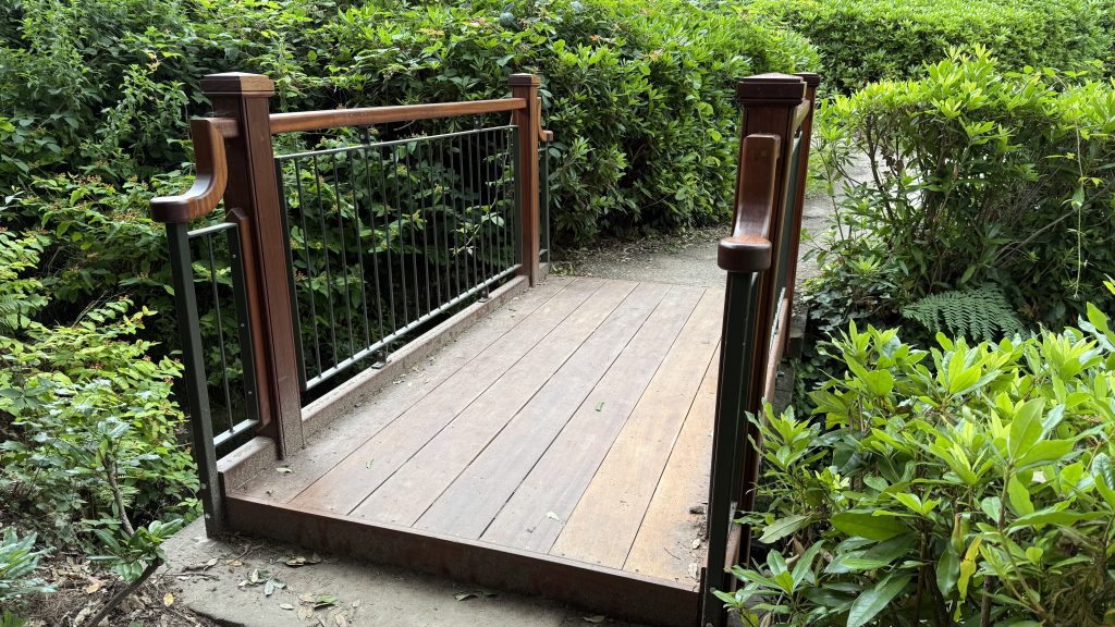 A wooden bridge with metal rails and polished handrails. 